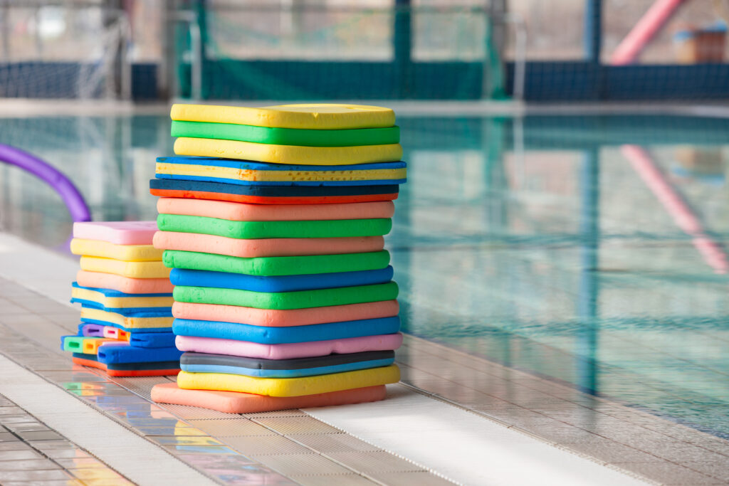 een stapel kleurrijke zwemplankjes aan de rand van het zwembad