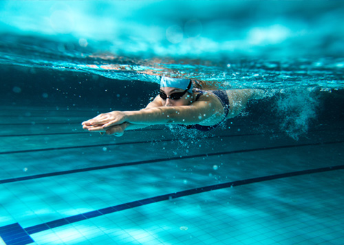 een vrouw duikt onder water in het zwembad
